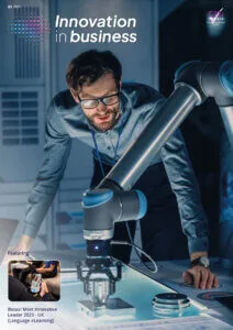 Cover image from magazine with a man inspecting a robot arm completing a task on a table